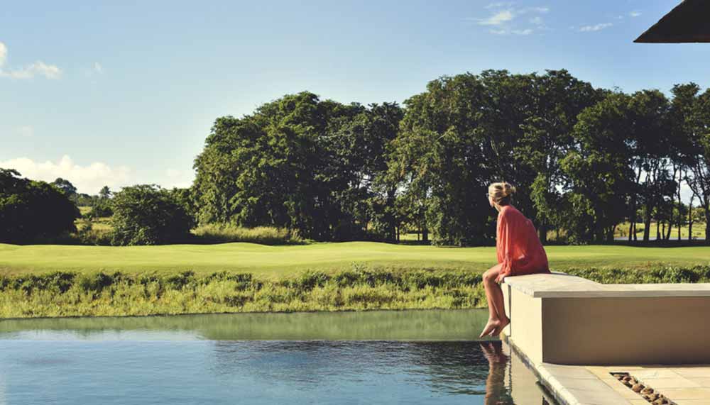 Bassin à débordement en bordure d'un parcours de golf à l'île Maurice, arbres tropicaux en arrière-plan.