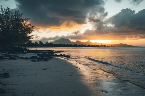 Littoral de l'île Maurice au coucher du soleil, rochers volcaniques et chaîne de montagnes à l'horizon