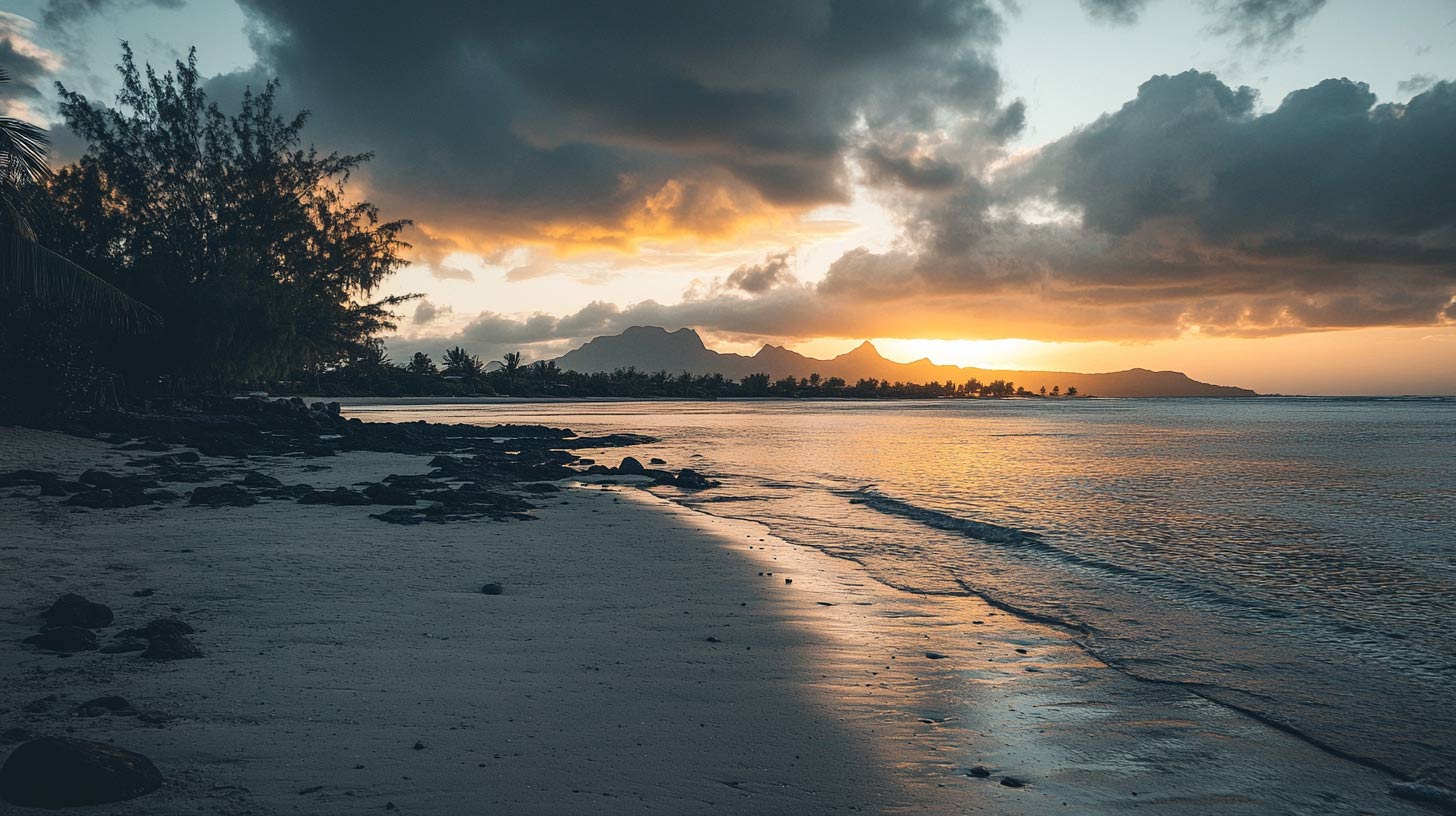 Littoral de l'île Maurice au coucher du soleil, rochers volcaniques et chaîne de montagnes à l'horizon