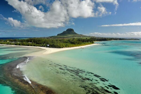 Vue aérienne d'un lagon turquoise et d'une plage de l'île Maurice sous les gros cumulus de l'été austral