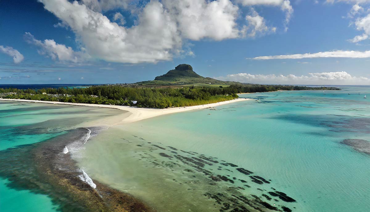 Vue aérienne d'un lagon turquoise et d'une plage de l'île Maurice sous les gros cumulus de l'été austral