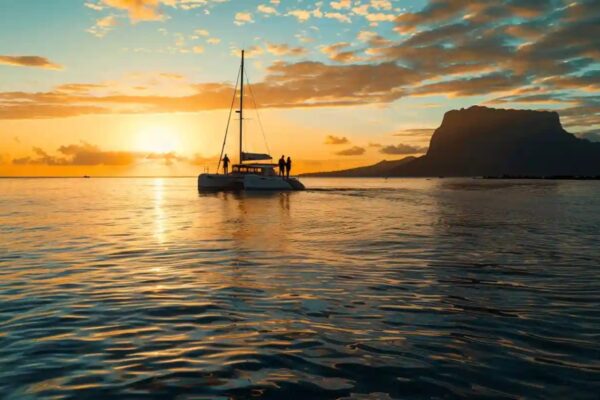 Catamaran au mouillage devant la silhouette d'une montagne, au coucher du soleil, à l'île Maurice