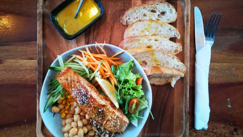 Assiette de poisson grillé, salade et pain servie sur un plateau en bois dans un restaurant