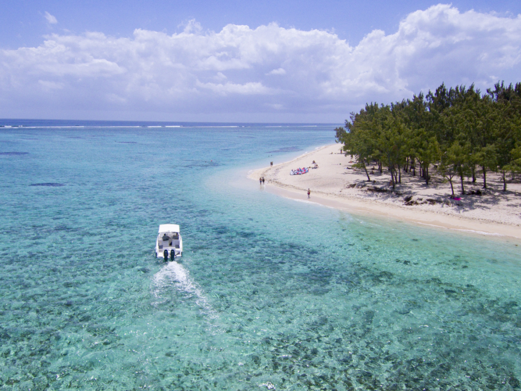 Vue aérienne d'un bateau approchant un banc de sable et d'une plage bordée de filaos à l'île Maurice