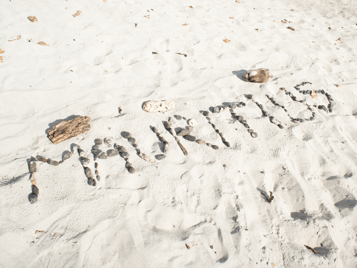 Le mot Mauritius écrit avec des galets sur le sable blanc d'une plage
