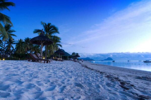 Plage de la côte ouest de l'île Maurice au crépuscule, transats et paillotes sous les filaos