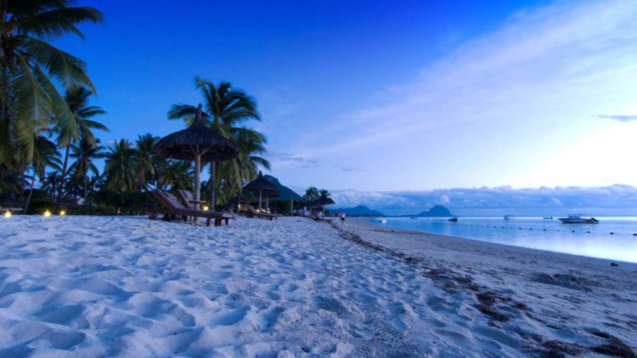 Plage de la côte ouest de l'île Maurice au crépuscule, transats et paillotes sous les filaos