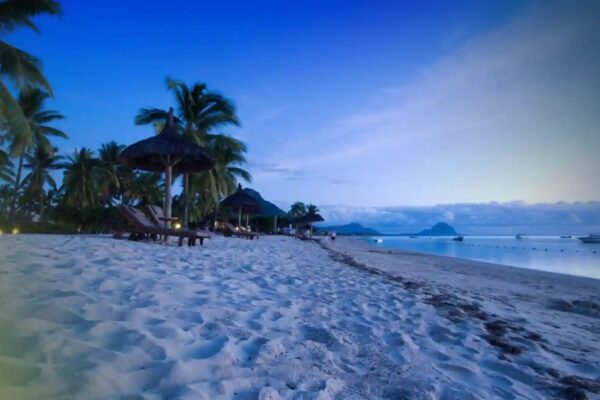 Plage de sable blanc de la côte ouest de l'île Maurice au crépuscule, avec la silhouette du Morne au fond