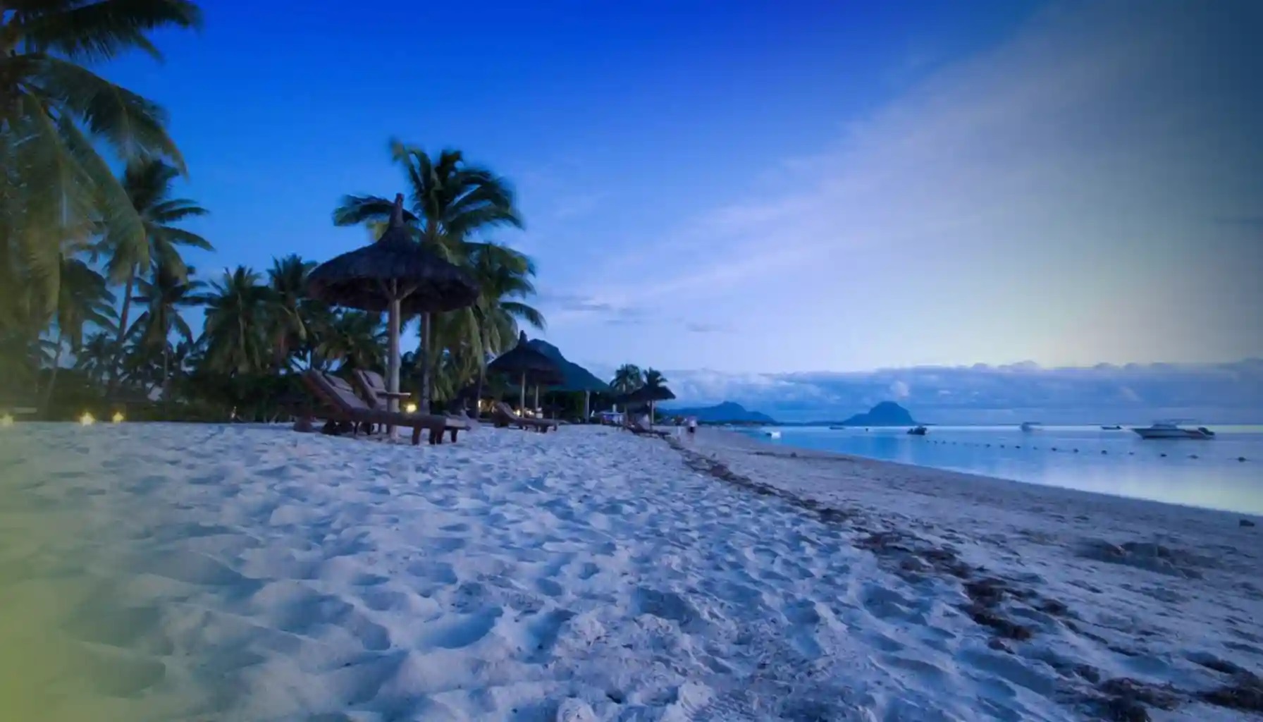 Plage de sable blanc de la côte ouest de l'île Maurice au crépuscule, avec la silhouette du Morne au fond
